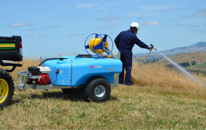 Person wearing PPE and spraying weeds from a TSX400 Trailed Sprayer