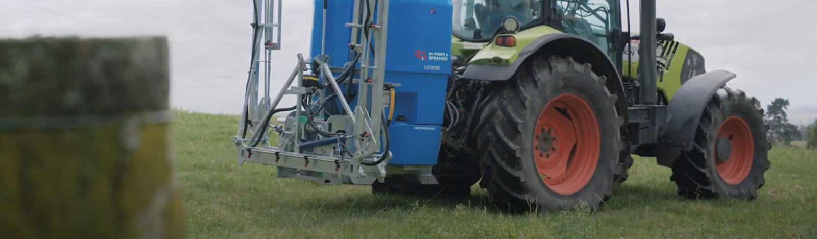 Tractor in a field with partially folded spray boom on an LS Linkage Sprayer