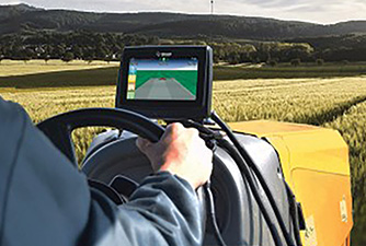 Farmer in a tractor cab using a GPS system to see where he has sprayed