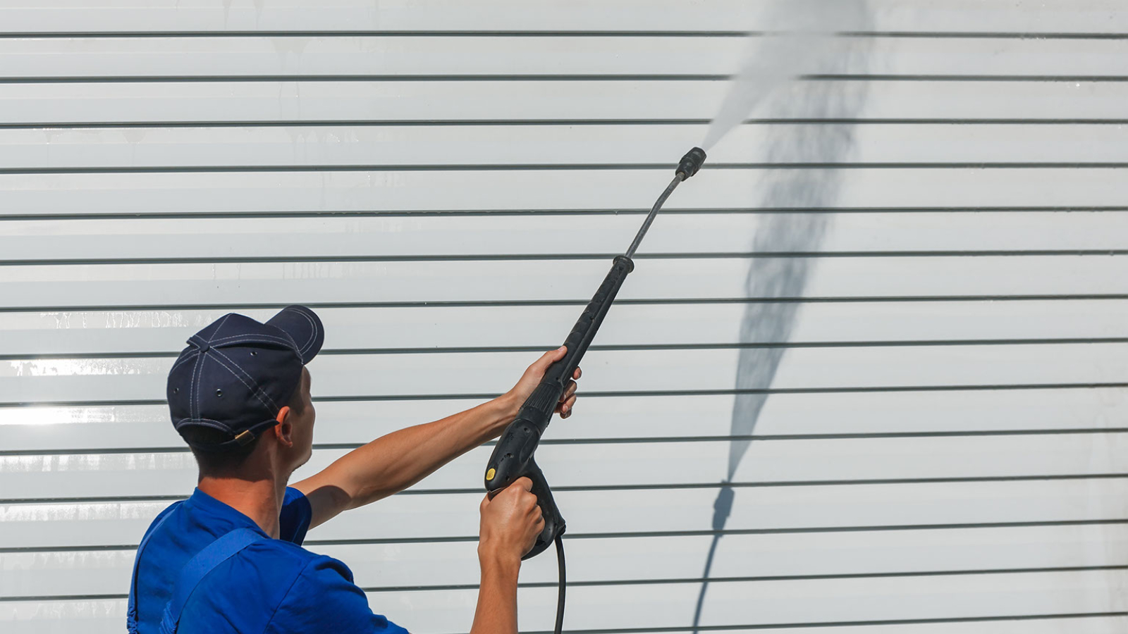 Person water blasting a wall
